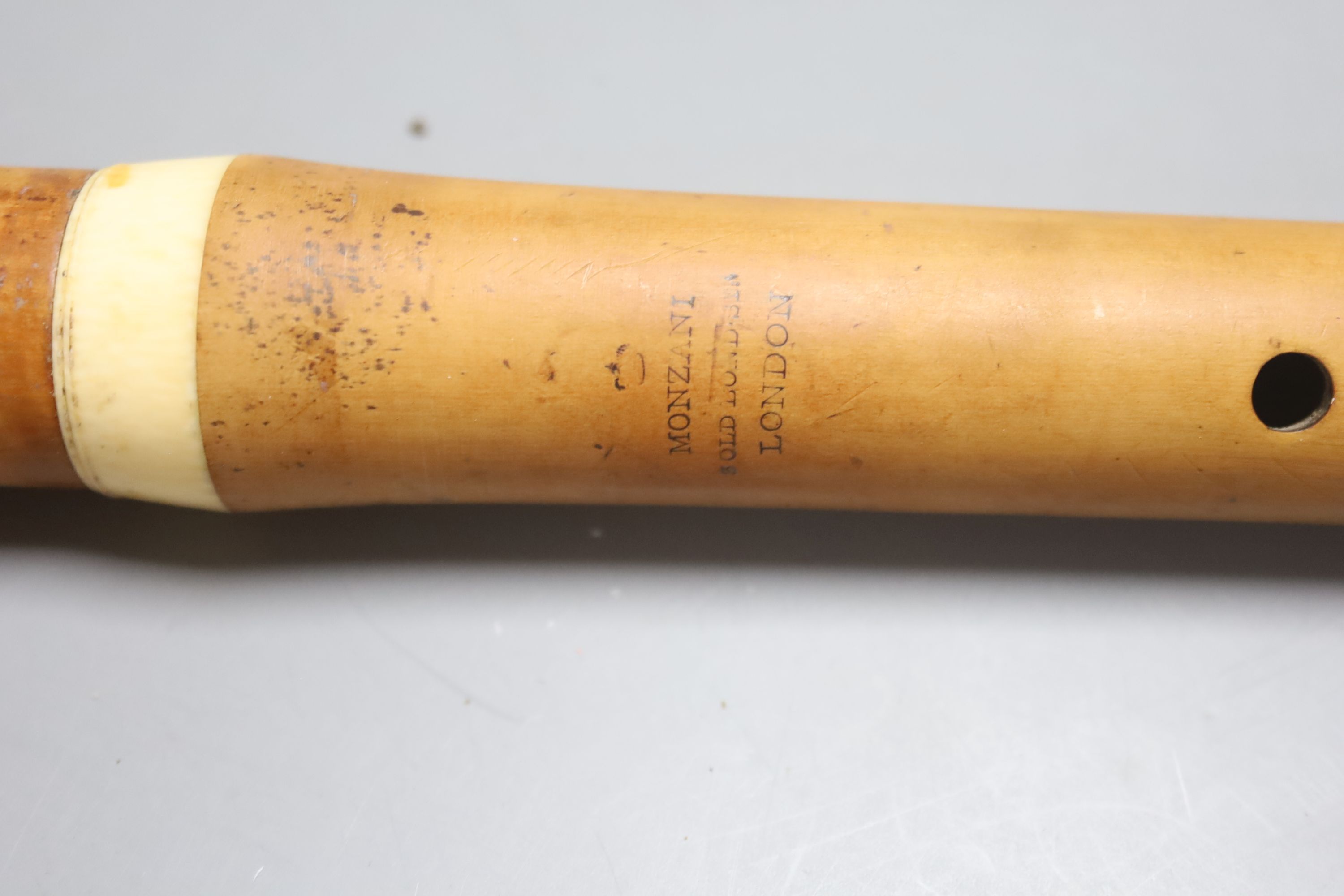 A three sectional Monzani flute with seven holes and a turned ivory cap and collars, stamped Monzari, Old Bona St , London, 19th centur